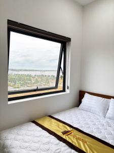 a bed in a room with a large window at LTC Hotel in Long Thành
