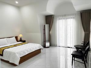 a bedroom with a bed and a desk and a window at LTC Hotel in Long Thành