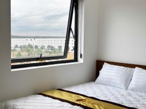 a bed in a room with a large window at LTC Hotel in Long Thành