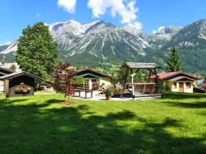 a green yard with houses and mountains in the background at Ramsauer Sonnenalm in Ramsau am Dachstein