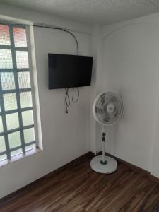 una stanza bianca con un ventilatore e una TV a schermo piatto di Villa Itzae Hotel - Piscina y Naturaleza a Viotá