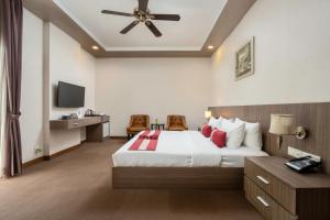 una camera da letto con un grande letto bianco con cuscini rossi di Clover Hotel a Phumĭ Prêk Chrey