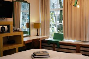 een slaapkamer met een bed en een groene stoel naast een raam bij Rosalia's Menagerie Cocktail bar & InnUpstairs in Amsterdam