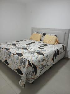 a bed with a black and white quilt and yellow pillows at La catalina in San Antonio