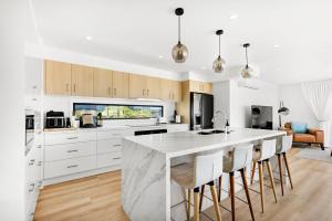 a kitchen with white cabinets and a large marble island at Bellagio - Swimming Pool with Ocean Views in Callala Beach