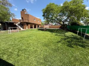 a large grass yard with a building and a tree at La catalina in San Antonio