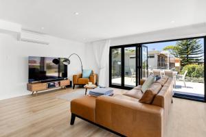a living room with a couch and a tv at Bellagio - Swimming Pool with Ocean Views in Callala Beach