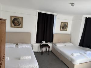 twee bedden in een kamer met zwarte gordijnen bij Birchwood-Lodge in Horley