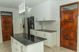 a kitchen with white cabinets and a black counter top at Grato Pacho in Kisumu