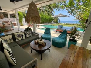 ein Wohnzimmer mit einem Sofa, Stühlen und einem Pool in der Unterkunft Villa Serenity Beachfront Bali in Pengastulan