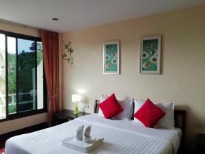 une chambre avec un grand lit avec des oreillers rouges dans l'établissement Baan-kawkaew-kata, à Ban Karon