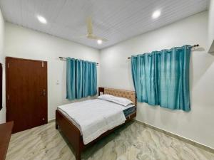 een slaapkamer met een bed en blauwe gordijnen bij vks holiday homes in Malpe