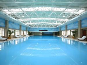 een groot zwembad met blauw water in een gebouw bij Teda Dalian in Dalian