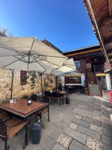 a patio with tables and chairs and umbrellas at Yi's Hostel in Shangri-La