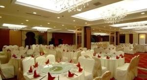 une grande salle de banquet avec des tables et des chaises blanches dans l'établissement Changchun Global Hotel, à Changchun