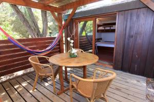 a wooden porch with a table and chairs and a hammock at Résidence Mobydick in Porto-Vecchio