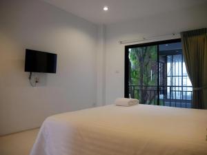 ein Schlafzimmer mit einem Bett, einem Fernseher und einem Fenster in der Unterkunft Sabai @ Chumphae Hotel in Chum Phae