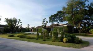 een tuin met struiken en bomen en een huis bij Baan Kula Mahasarakam in Ban Nong Chik