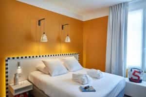 una camera da letto con un letto bianco e pareti arancioni di Hotel Mercure Brest Centre Les Voyageurs a Brest