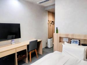 een hotelkamer met een bureau, een tv en een bed bij New Grand Hotel in Shinjo