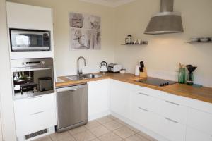 a kitchen with white cabinets and a sink and a microwave at Cottesloe Sea Bliss Apartment in Perth