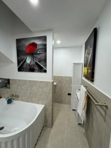 een badkamer met een badkuip en een afbeelding van een vrouw met een rode paraplu bij Brigidas Guest House in Bairnsdale +25 foto's
