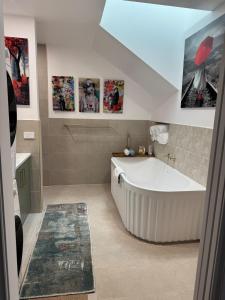 een groot wit bad in een badkamer met foto's aan de muur bij Brigidas Guest House in Bairnsdale