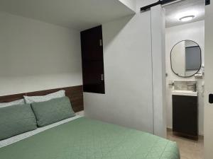 een slaapkamer met een groen bed en een spiegel bij Pequeño Alojamiento in Cancun