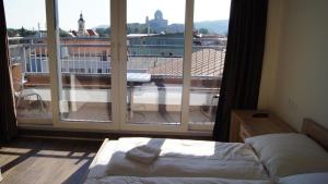 a bedroom with a bed and a large window at Apartman Panorama in Štúrovo