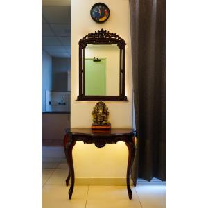a table with a mirror on a wall with a clock at Kimaya's Abode in Chandīgarh