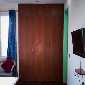a large wooden cabinet in a bedroom with a tv at Kimaya's Abode in Chandīgarh