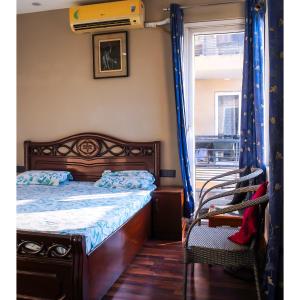 a bedroom with a bed and a chair and a window at Kimaya's Abode in Chandīgarh