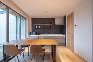 eine Küche und ein Esszimmer mit einem Holztisch und Stühlen in der Unterkunft tango resort ragura kitsu bettei in Kyōtango