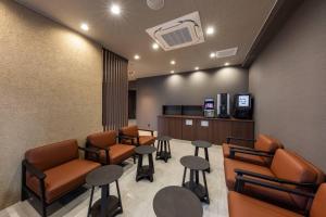a waiting room with chairs and tables and a tv at Apartment Hotel YAEZAKI in Beppu