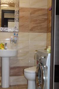 een badkamer met een toilet, een wastafel en een wasmachine bij Apartments on Chkalova in Majkop