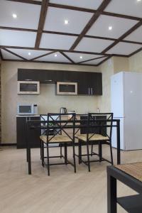a kitchen with a table and chairs and a refrigerator at Apartments on Chkalova in Maykop