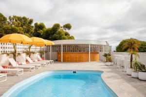 a pool in front of a building with chairs and umbrellas at Sunnymead Hotel in Aireys Inlet