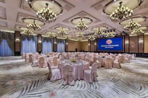 ein Bankettsaal mit weißen Tischen und Stühlen und Kronleuchtern in der Unterkunft Haoyikang Hotel in Huizhou + 136 Fotos