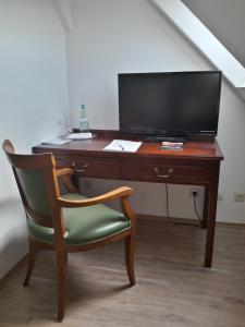einen Schreibtisch mit einem Stuhl und einem TV darauf in der Unterkunft Kloster-Remise Wöltingerode in Goslar