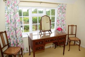 a dressing table with a mirror and two chairs and a window at The Old Bakery, Long Street in Enford