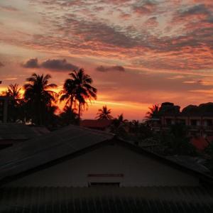 ein Sonnenuntergang mit Palmen und Gebäuden im Vordergrund in der Unterkunft haadrin village DC in Haad Rin