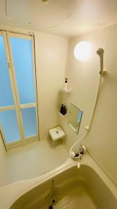 een badkamer met een bad, een raam en een spiegel bij Apartment Hotel YAEZAKI in Wada +51 foto's