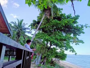 Ein Mann steht auf einer Veranda neben dem Strand in der Unterkunft LOwayalailaiSTAY in Wayasewa Island