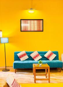 a yellow living room with a blue couch and a table at Pinevilla homestay in Jorhat