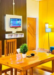 a dining room with a wooden table and a tv at Pinevilla homestay in Jorhat