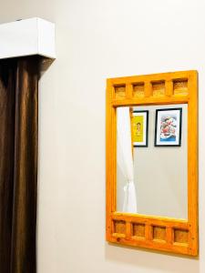 a mirror with a wooden frame on a wall at Pinevilla homestay in Jorhat