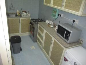 une petite cuisine avec un four micro-ondes sur un comptoir dans l'établissement العين الهيلي مصباح ب1, à Al-Aïn