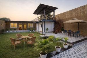 a house with a patio with a table and chairs at Mud Meadows - Peace and Tranquility 3br Farm in Faridabad