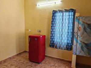 a red refrigerator in a room with a window at Nilan Aarudhra Homestay in Chidambaram