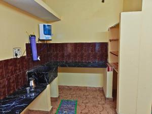 a kitchen with a black counter top and a tv at Nilan Aarudhra Homestay in Chidambaram +18 photos